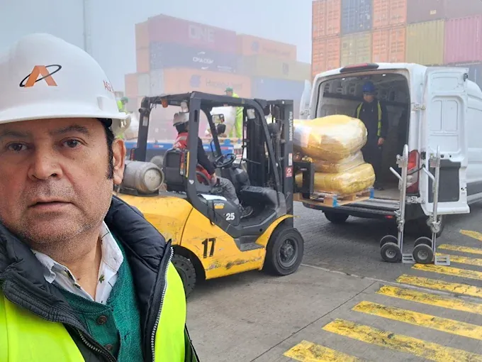 Agente de aduanas junto a una grúa horquilla que carga una camioneta en un recinto portuario